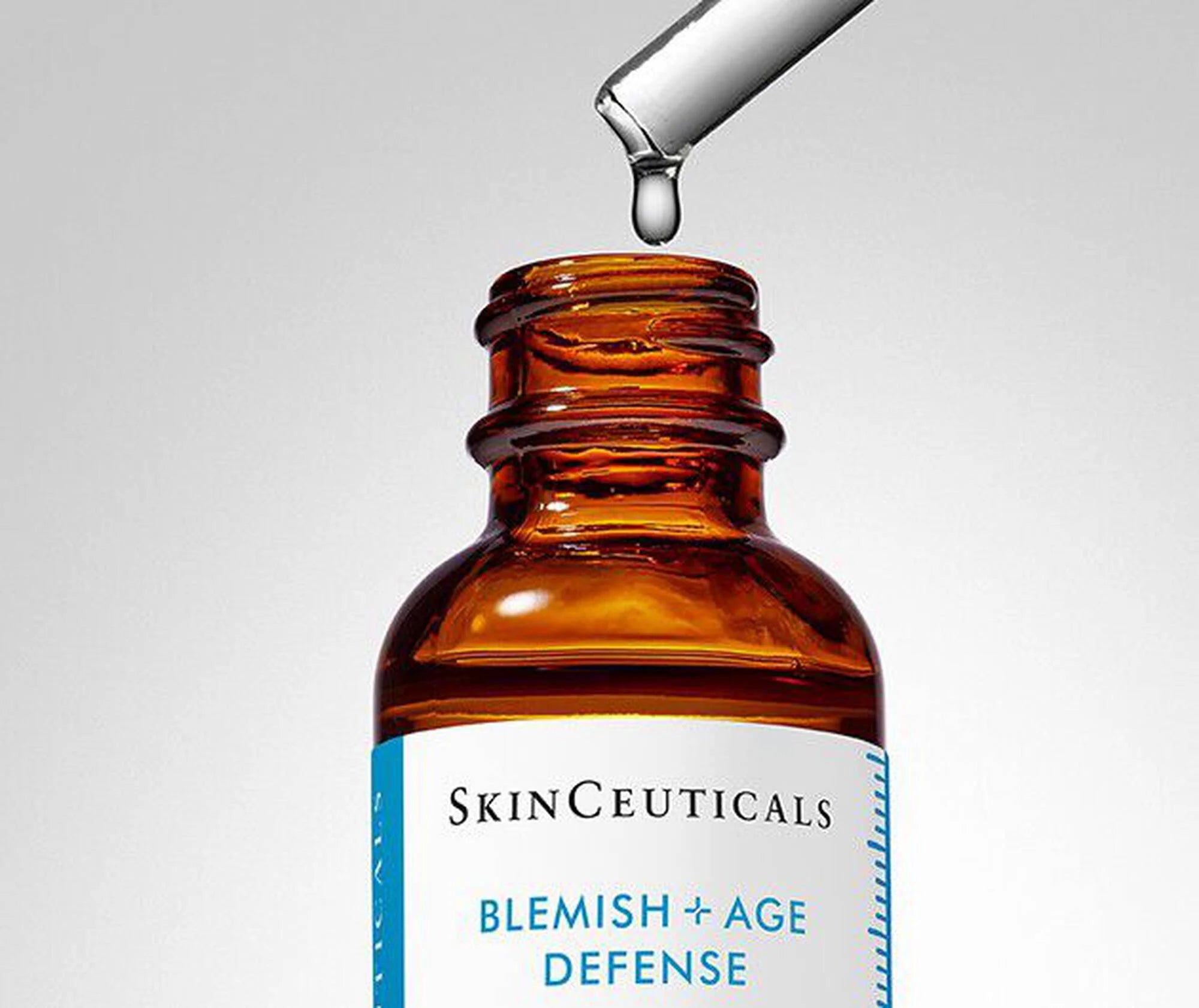 SkinCeuticals Blemish + Age Defense serum bottle with dropper on a gray background