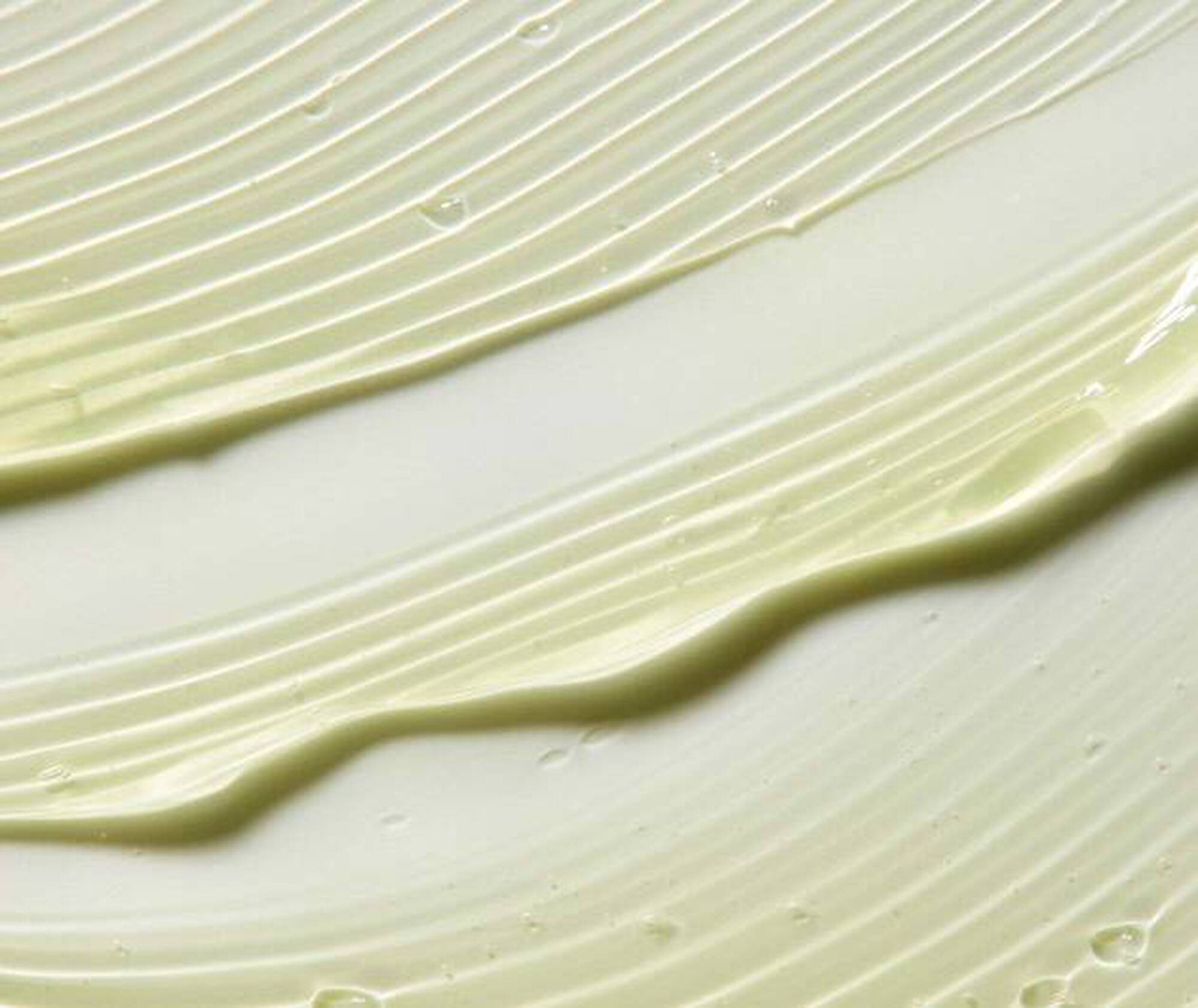 Close-up of green cream or paint with wavy patterns on a light background
