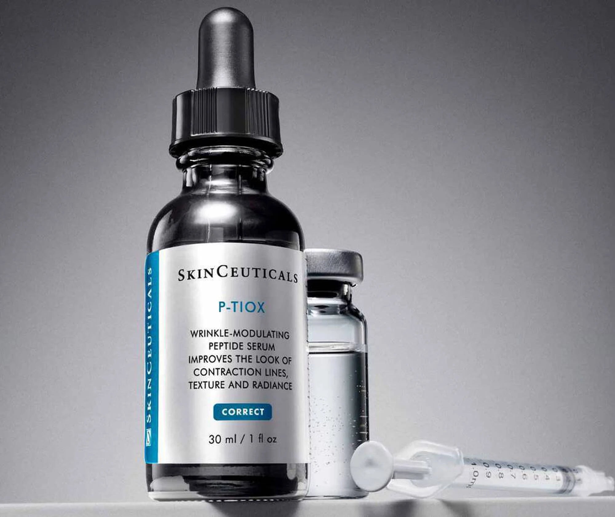 SkinCeuticals P-TRIOX skincare serum with dropper and syringe on a gray background