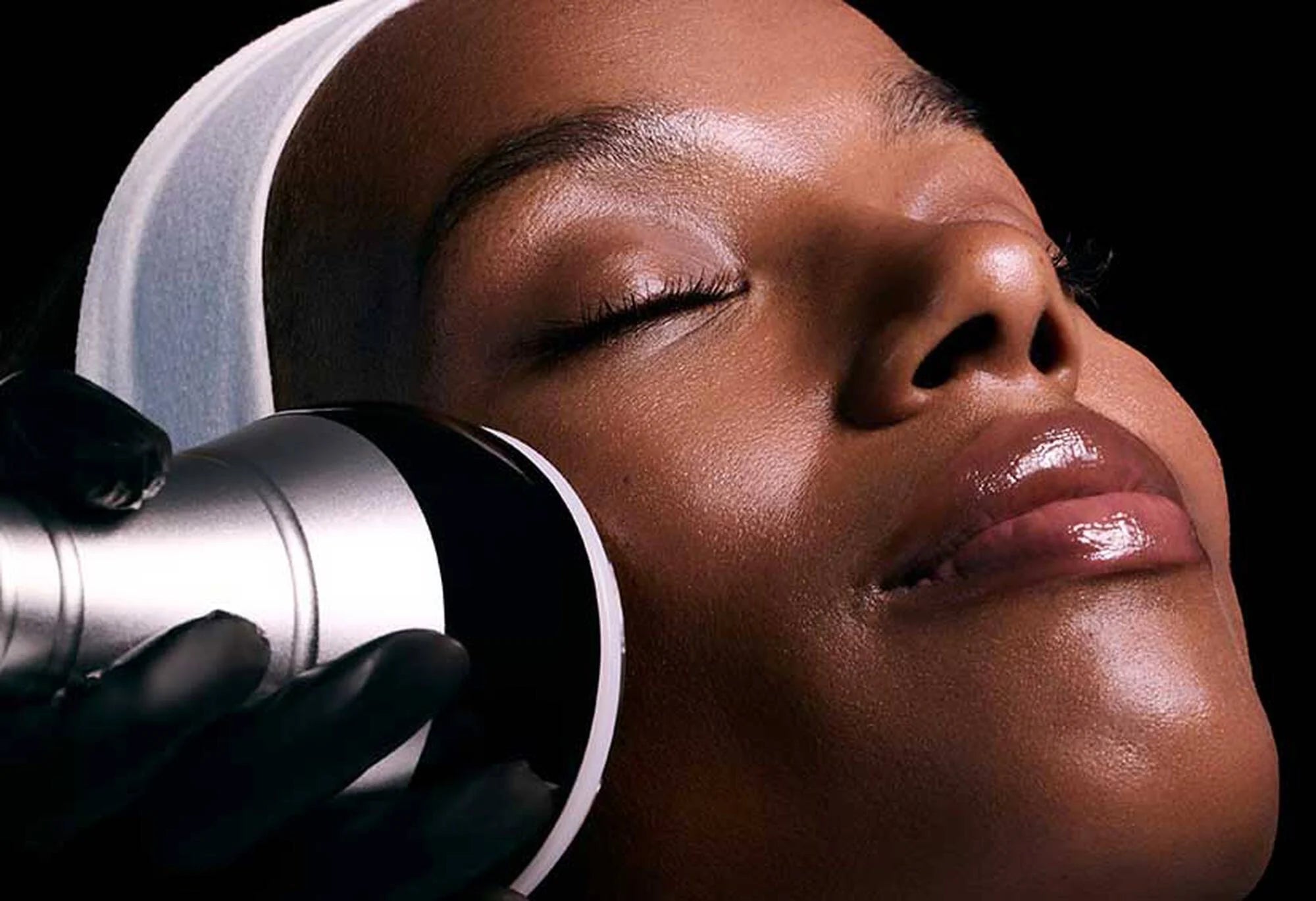 Close-up of a person's face with a device on their cheek against a black background