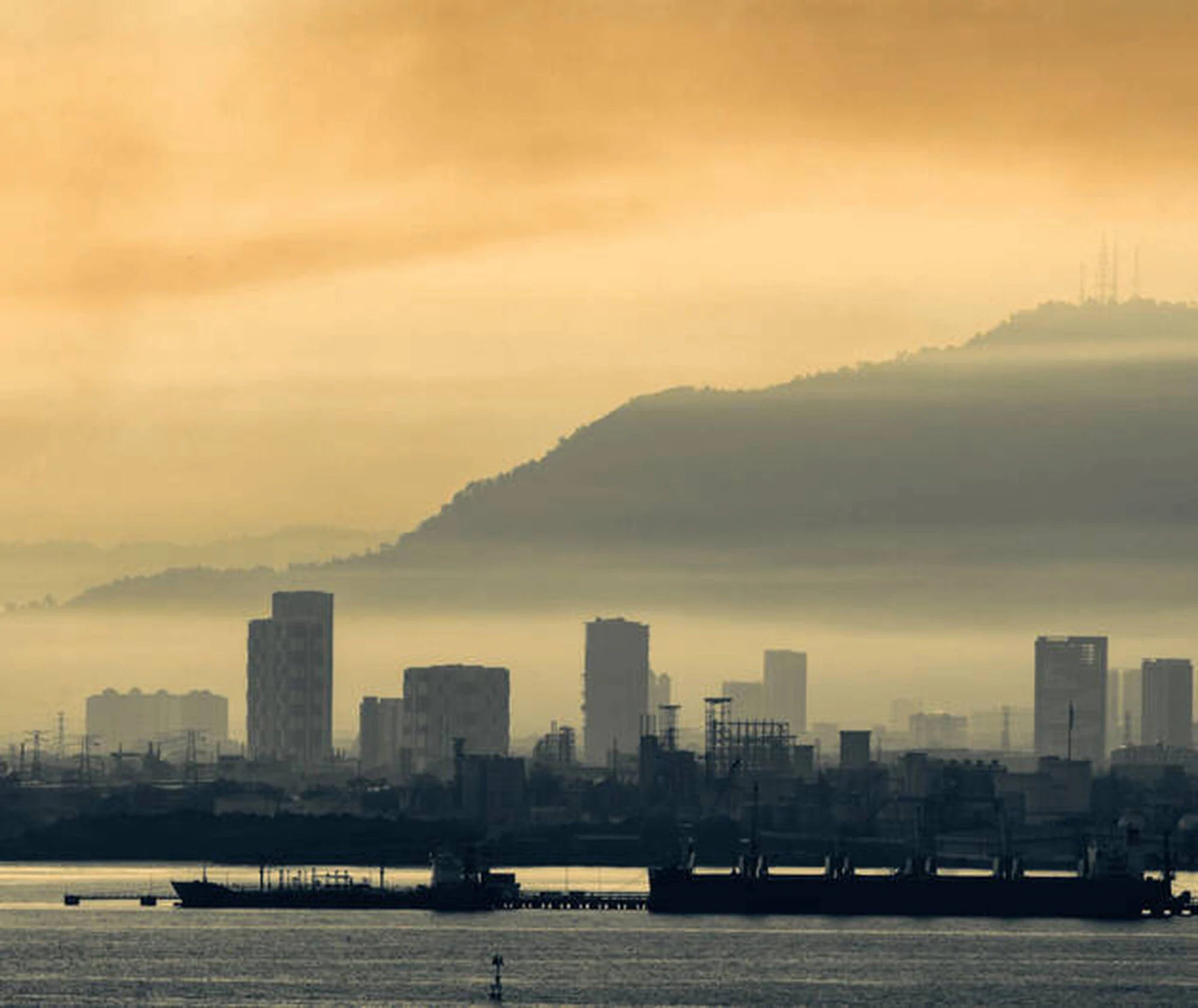 City skyline with mountains in the background during sunset.