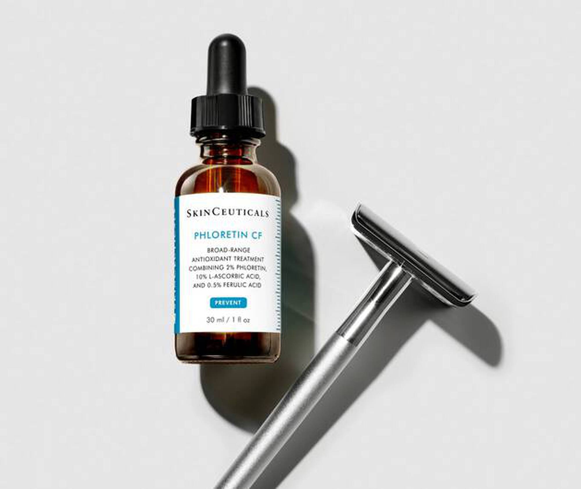 SkinCeuticals Phloretin CF bottle with a razor on a light gray background
