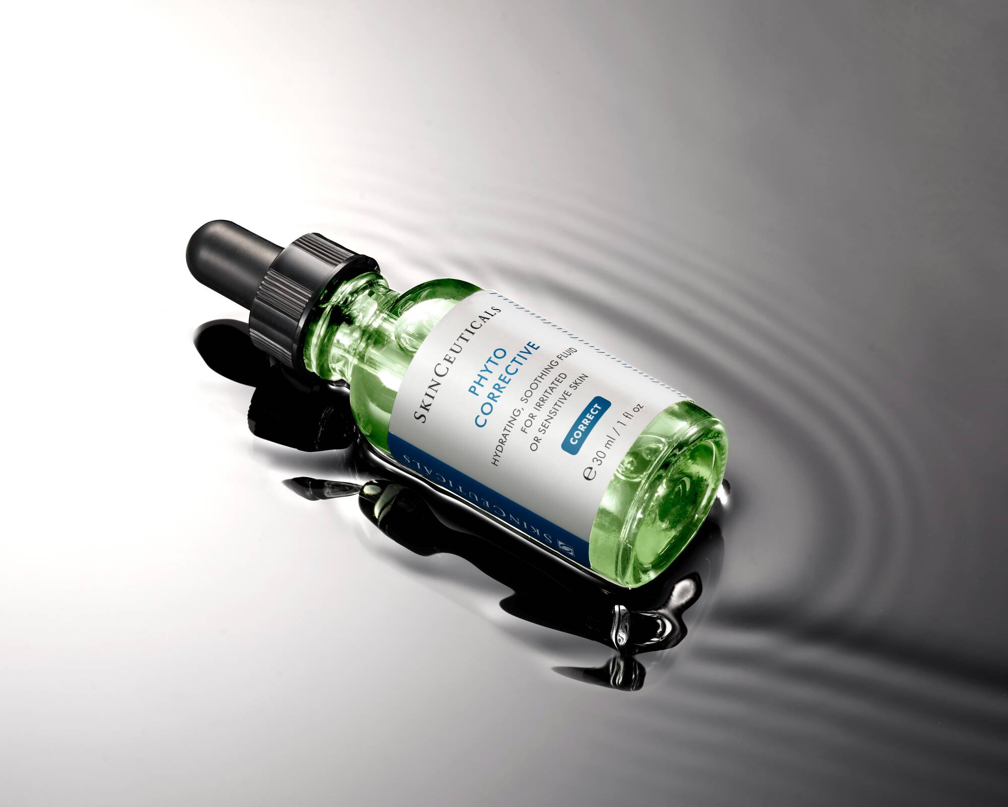 Skincare serum bottle with dropper on a reflective surface