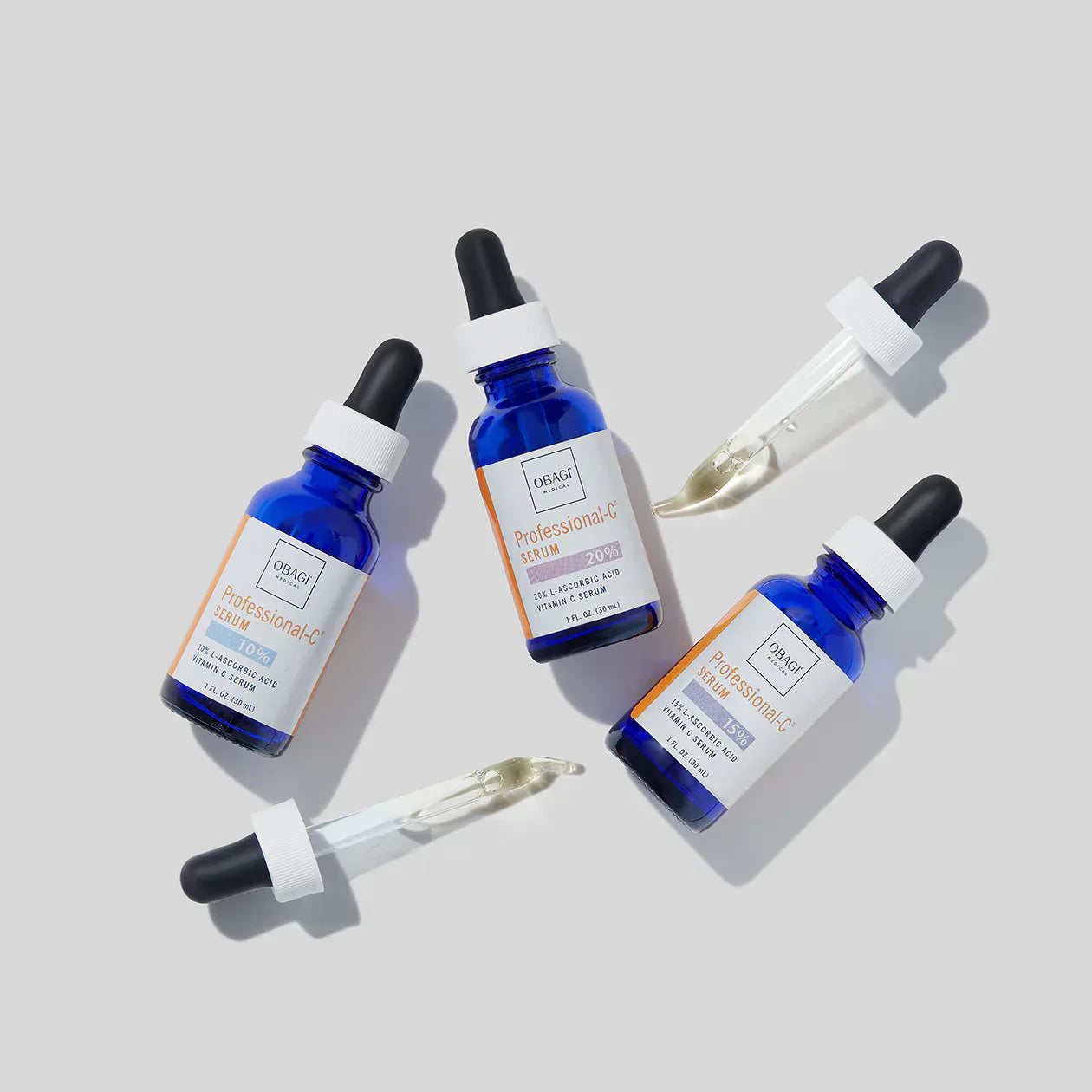 Three bottles of a skincare serum with droppers on a light gray background