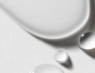Close-up of a white ceramic plate with water droplets on a light gray background