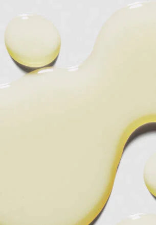 Close-up of a yellow liquid droplet on a white surface