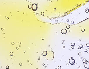 Close-up of oil and water layers with bubbles on a yellow and white background