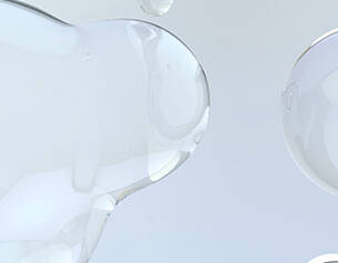 Close-up of a clear liquid being poured into a glass container on a light gray background