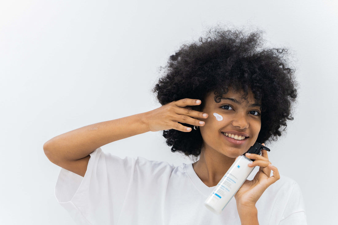 Woman applying cream to her face with a white background