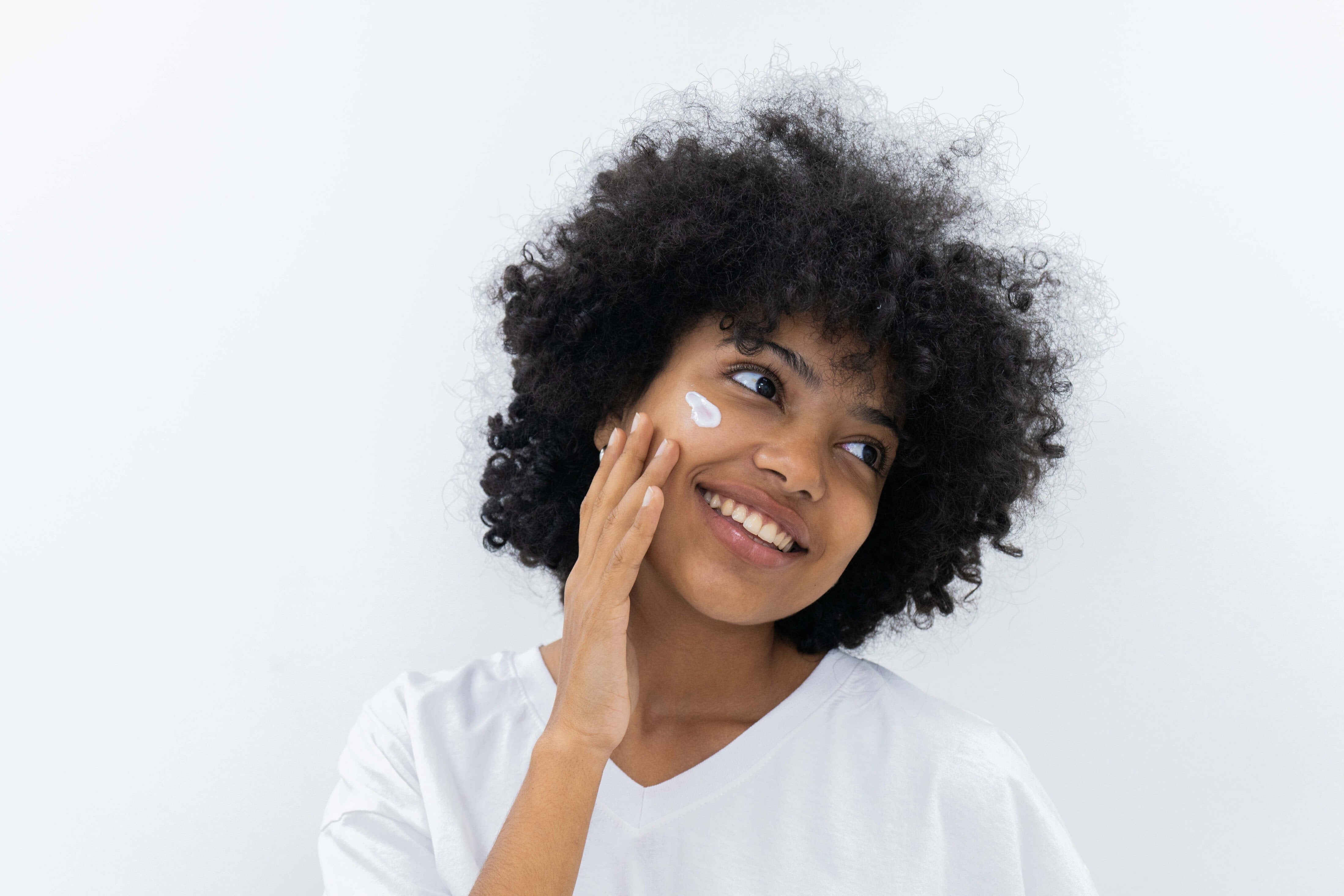 Woman applying cream to her face with a white background