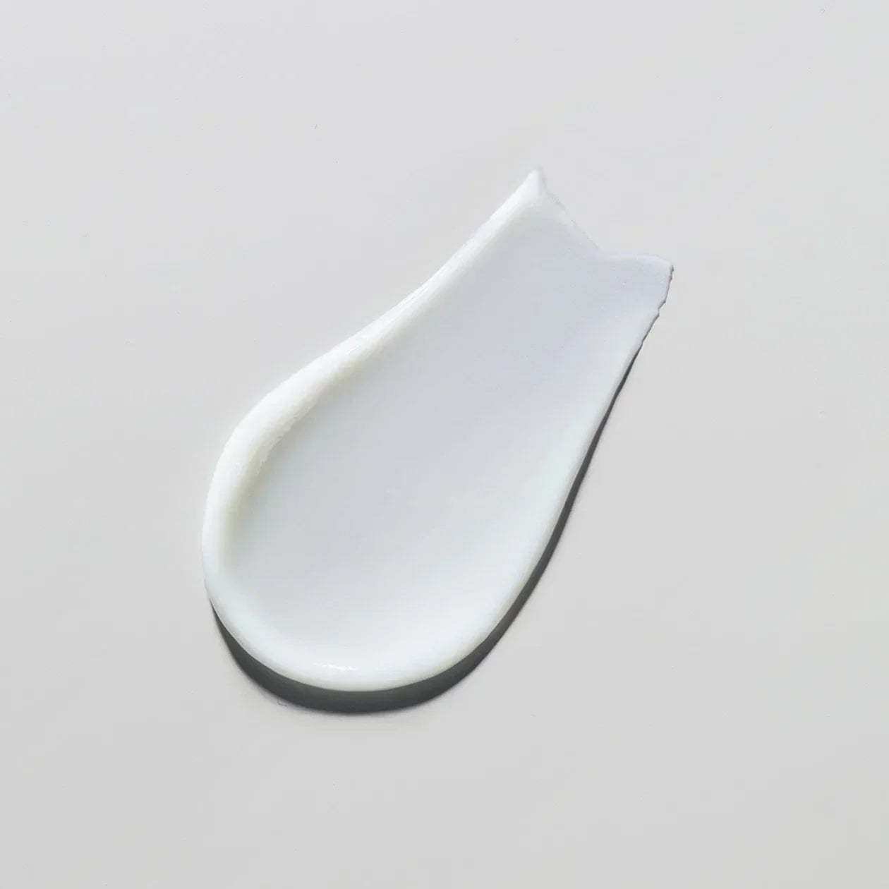 White cream smear on a light gray background