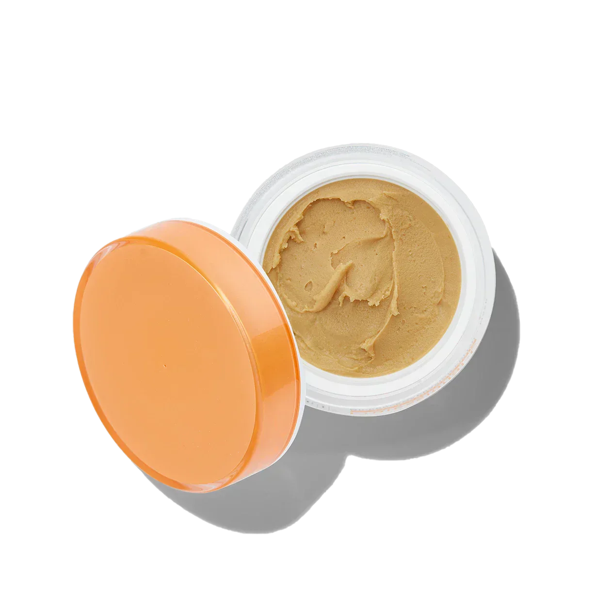 Open jar of beige cream with an orange lid on a white background