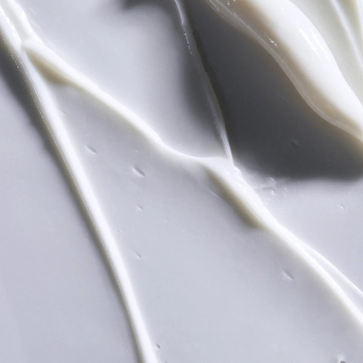Close-up of white cream or paint on a gray background