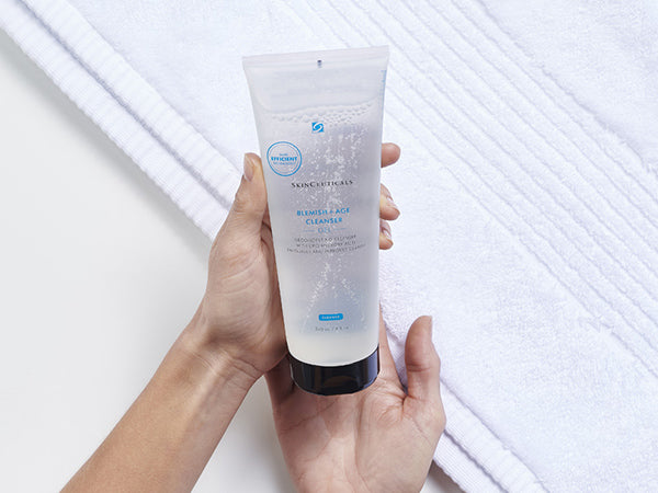 Hand holding a tube of Skinceuticals product on a white background