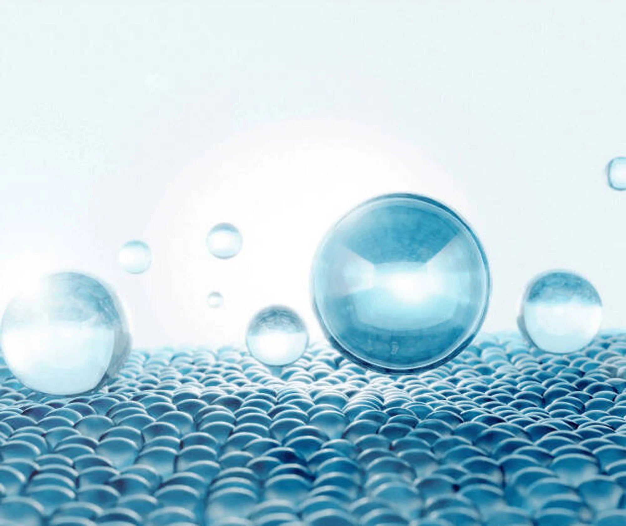 Blue water droplets on a textured surface with a light blue gradient background