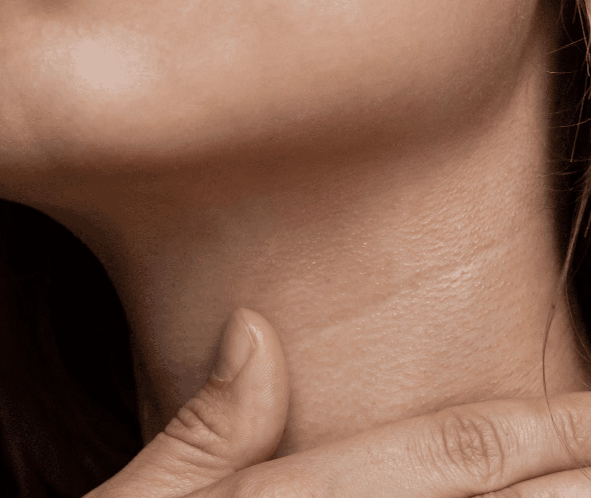 Close-up of a person's neck and shoulder with a hand gently touching the skin