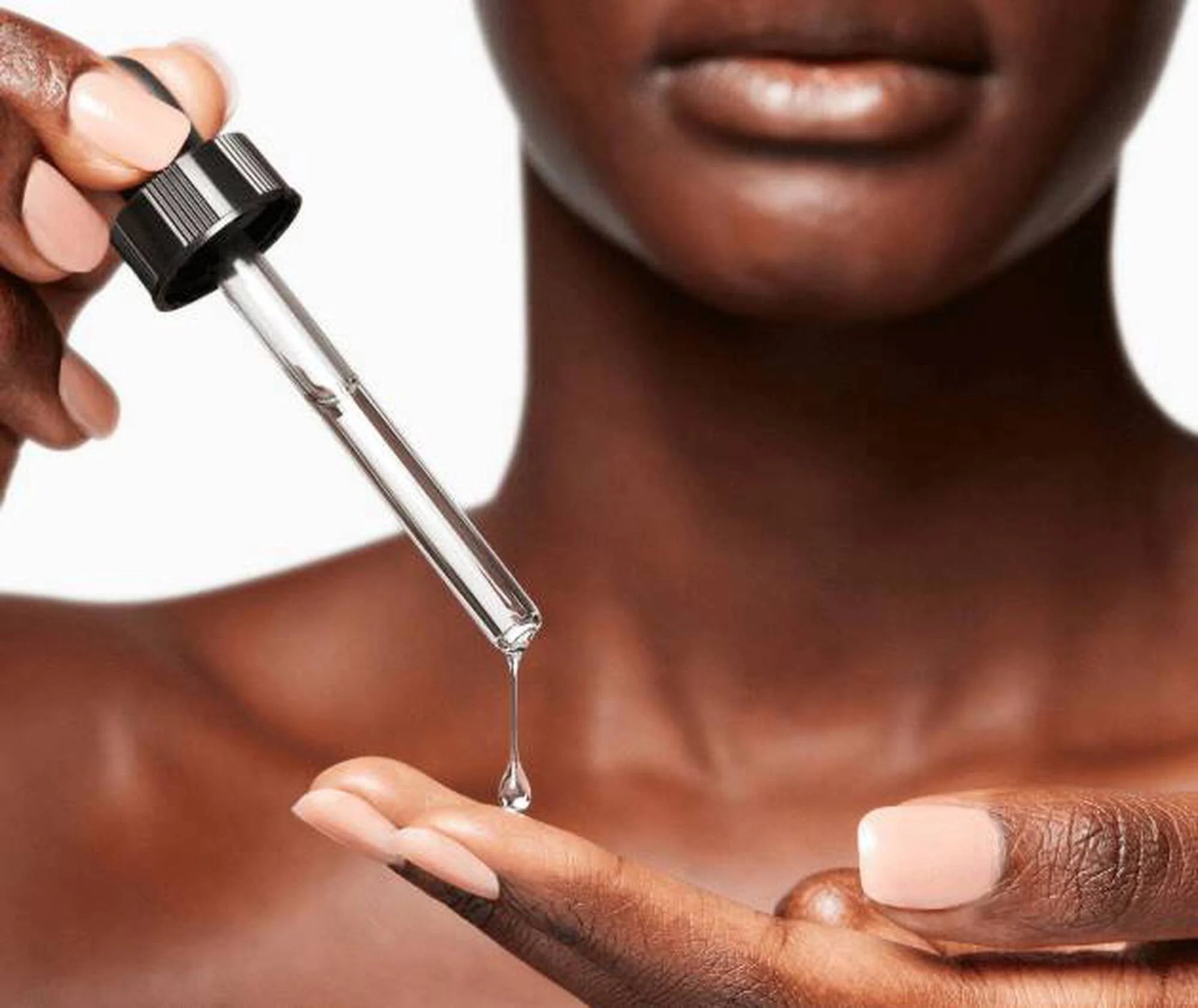 Person holding a dropper with a close-up of skin texture.